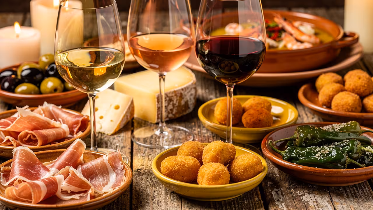 Verschillende soorten wijn tussen de tapas op een rustieke houten tafel